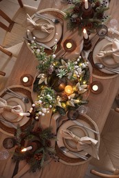 Photo of Christmas celebration. Festive table setting with dishware, glasses and decor in room, top view