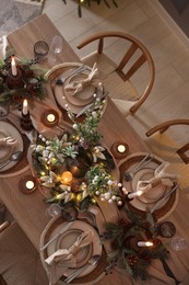 Photo of Christmas celebration. Festive table setting with dishware, glasses and decor in room, top view