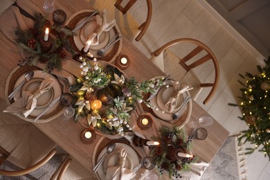 Photo of Christmas celebration. Festive table setting with dishware, glasses and decor in room, top view