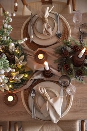 Photo of Christmas celebration. Festive table setting with dishware, glasses and decor in room, top view