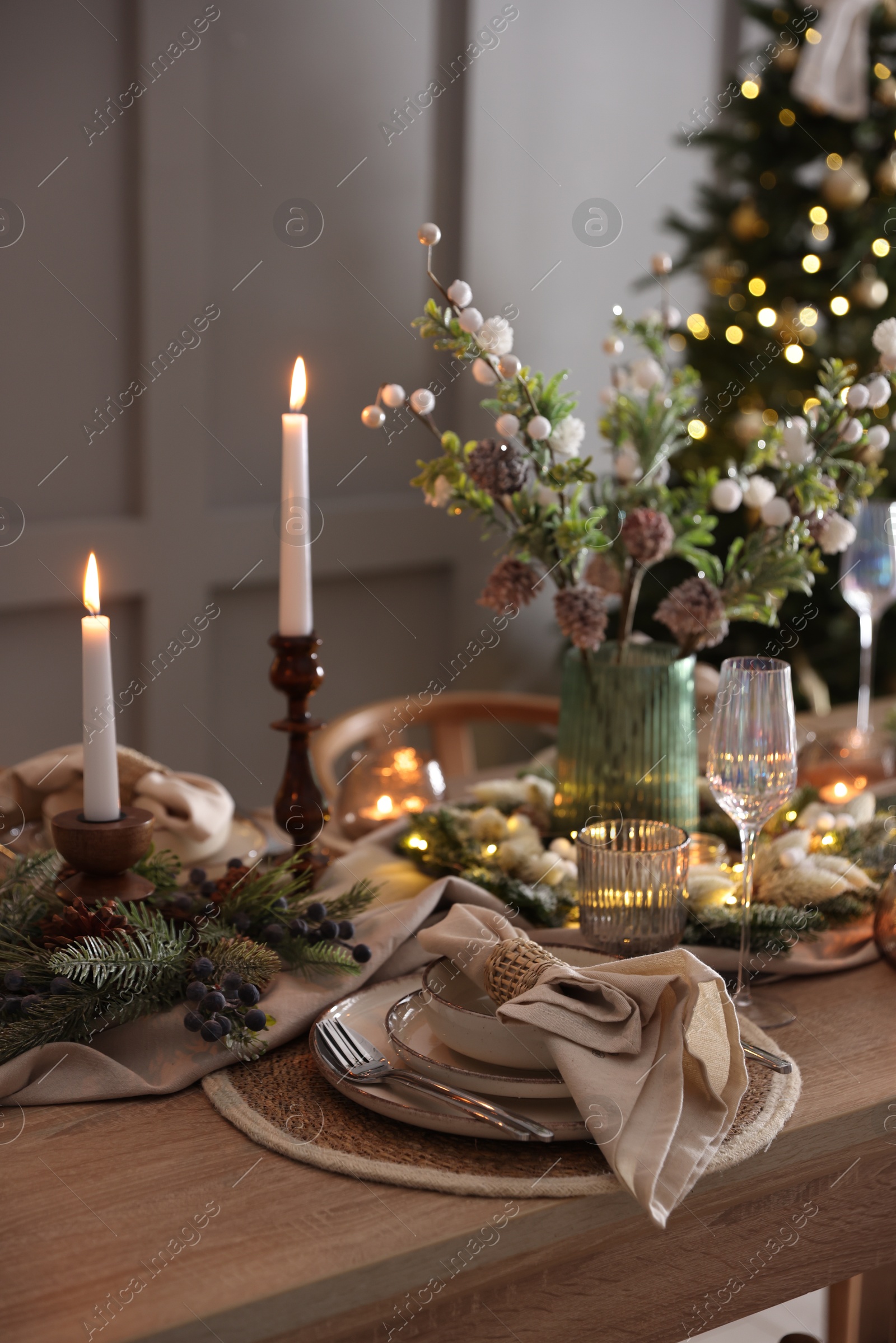 Photo of Christmas celebration. Festive table setting with dishware, glasses and decor in room