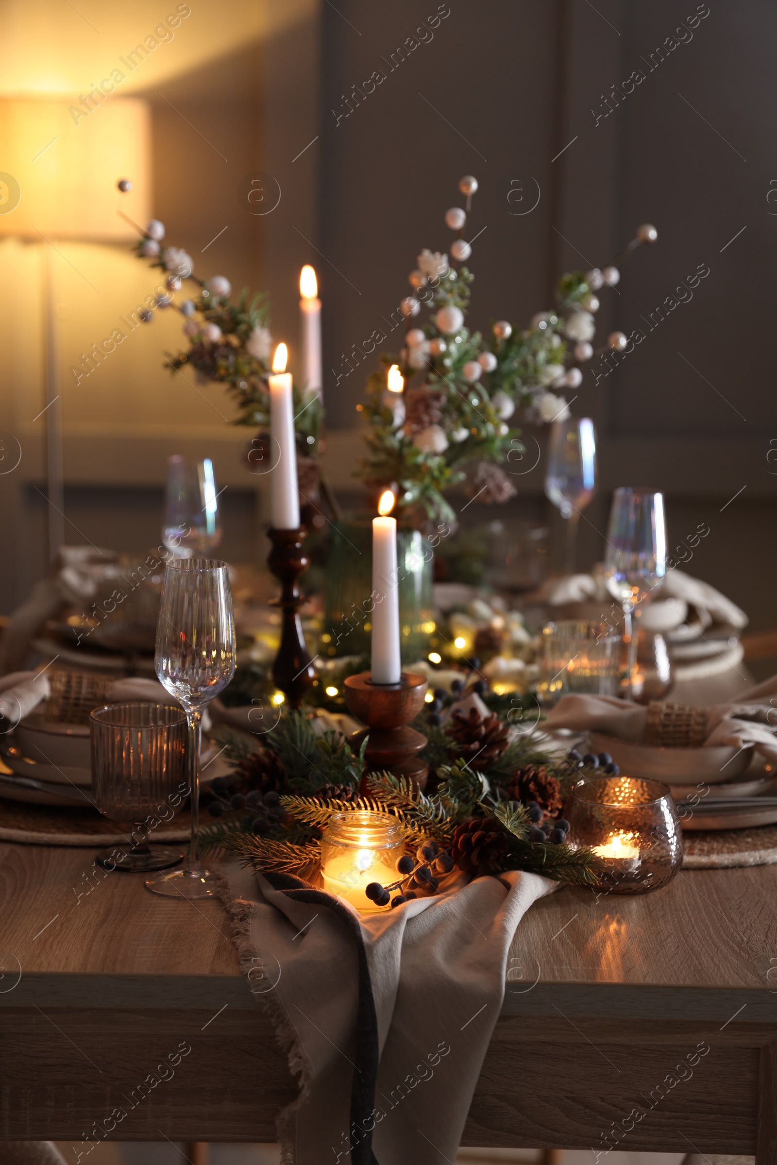 Photo of Christmas celebration. Festive table setting with dishware, glasses and decor in room