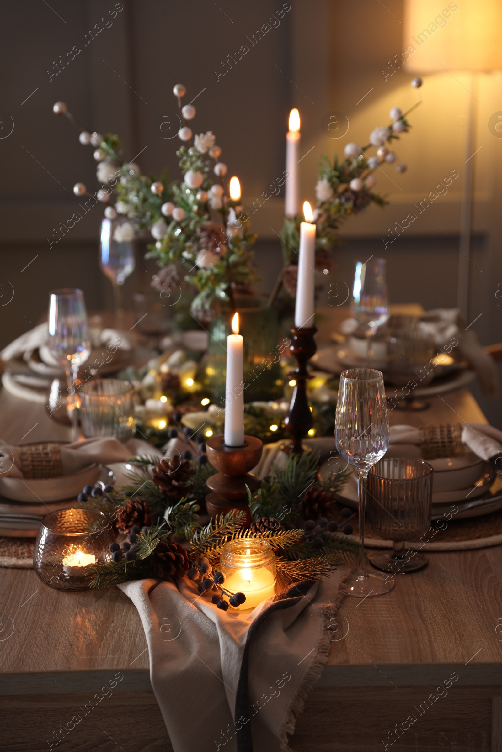 Photo of Christmas celebration. Festive table setting with dishware, glasses and decor in room