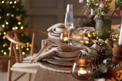 Photo of Christmas celebration. Festive table setting with dishware, glasses and decor in room