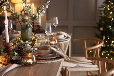 Photo of Christmas celebration. Festive table setting with dishware, glasses and decor in room