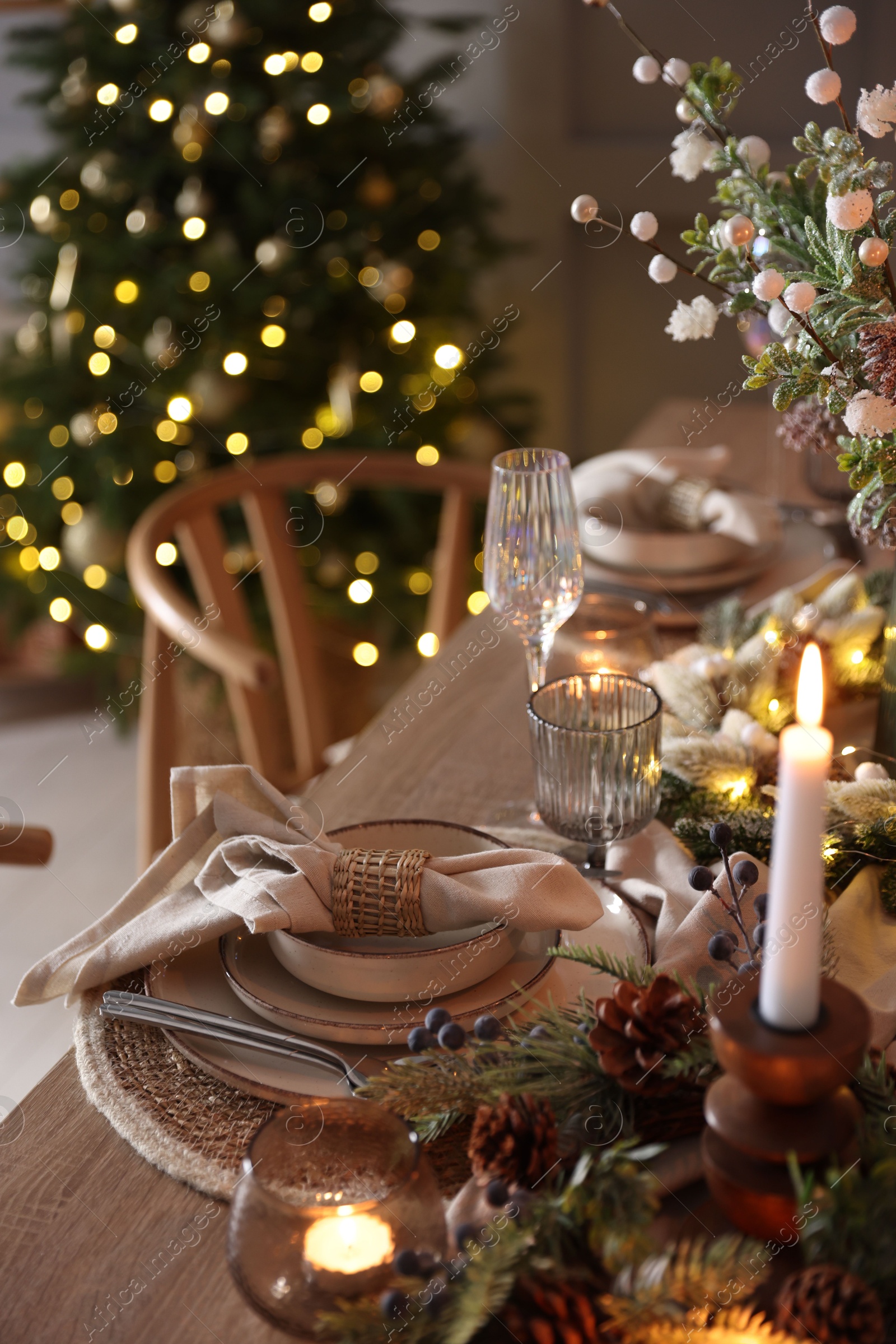 Photo of Christmas celebration. Festive table setting with dishware, glasses and decor in room