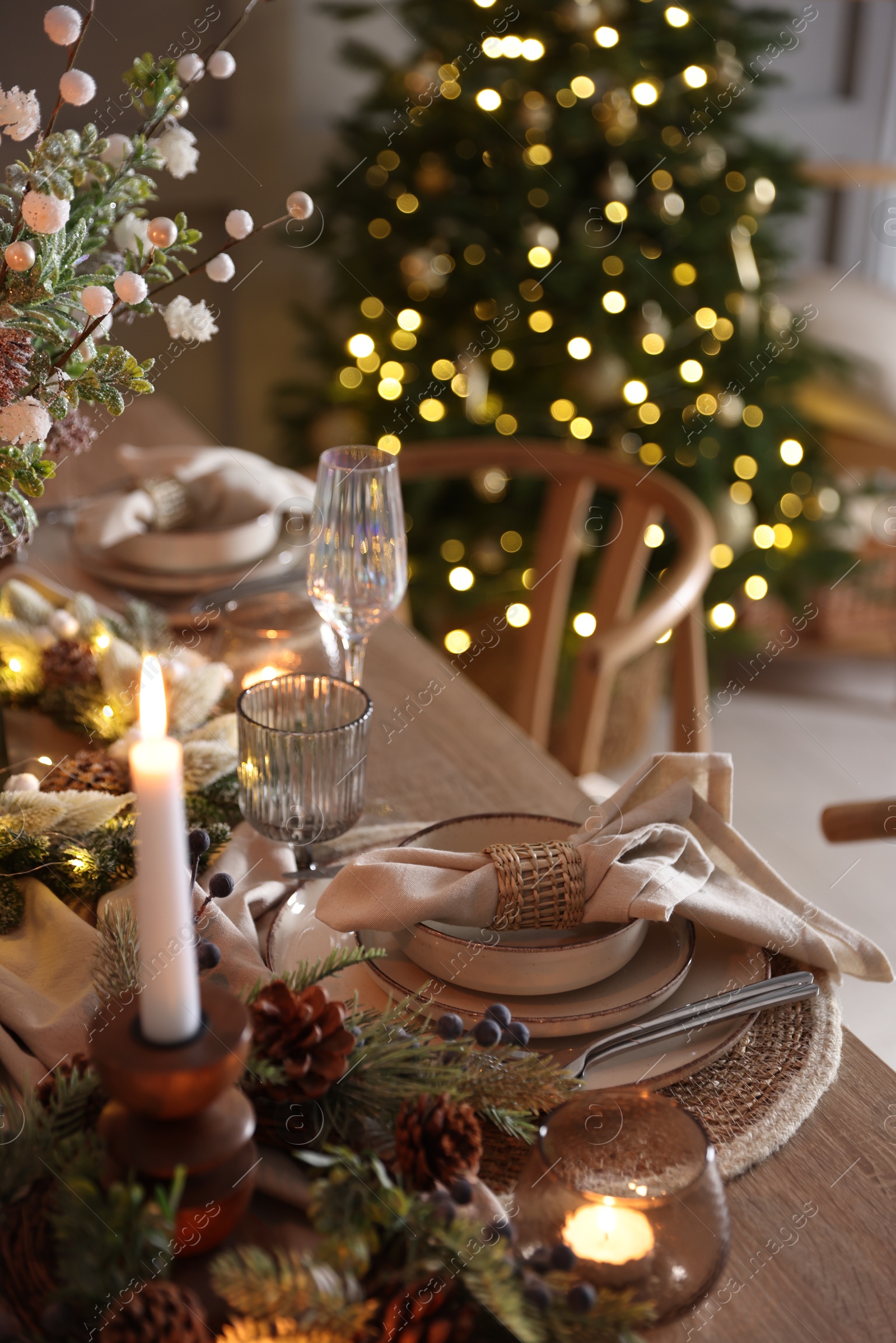 Photo of Christmas celebration. Festive table setting with dishware, glasses and decor in room