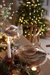 Photo of Christmas celebration. Festive table setting with dishware, glasses and decor in room