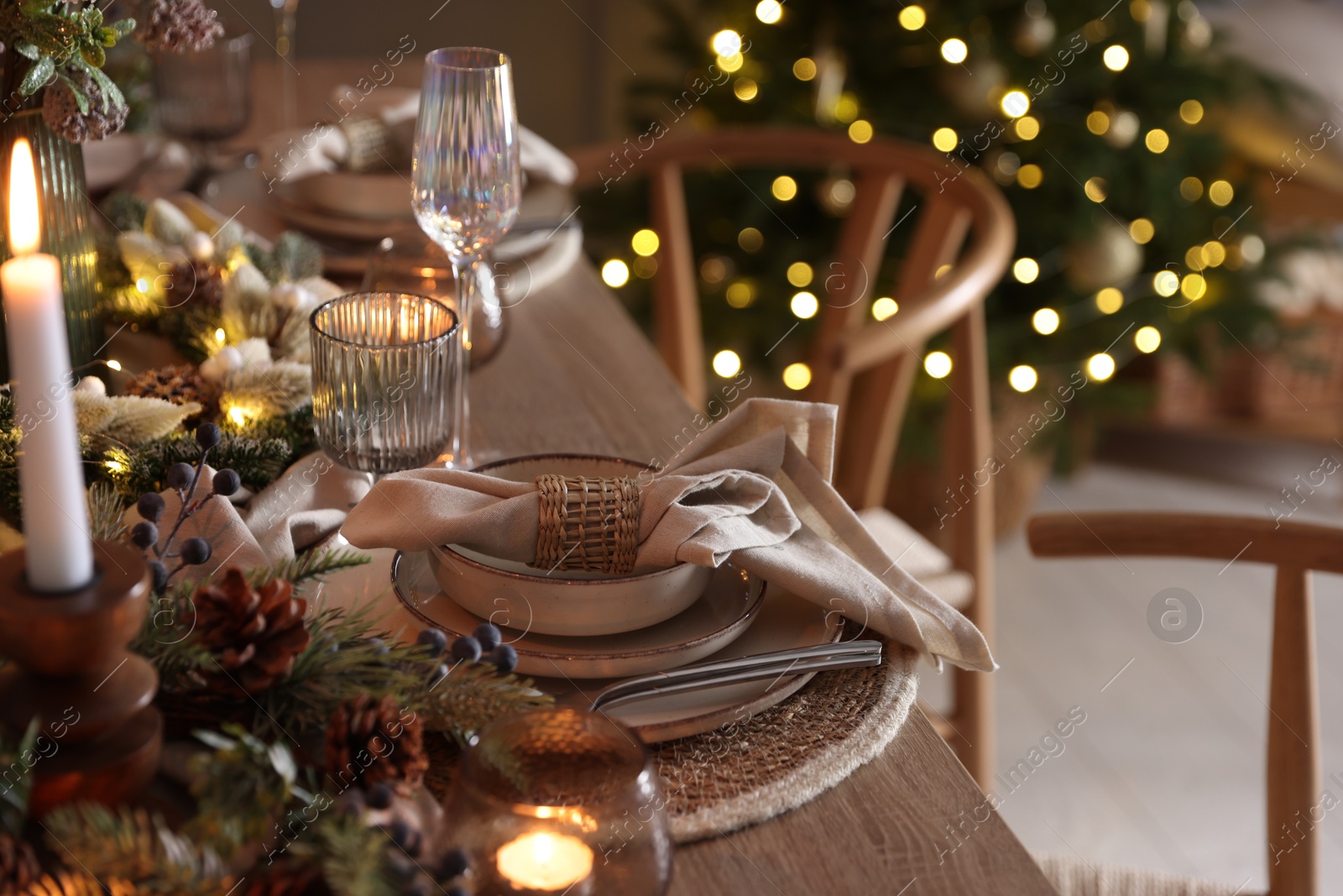 Photo of Christmas place setting with festive decor on wooden table in room