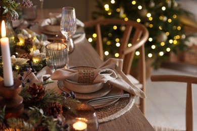 Photo of Christmas place setting with festive decor on wooden table in room