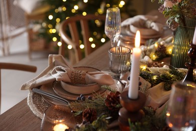 Photo of Christmas place setting with festive decor on wooden table in room, closeup