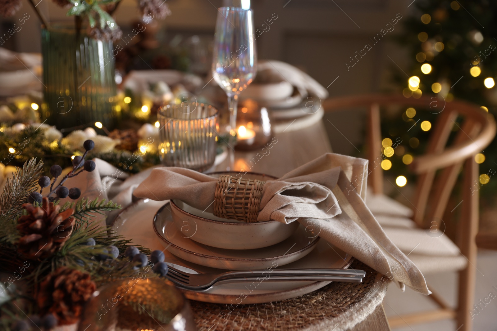 Photo of Christmas place setting with festive decor on table in room, closeup