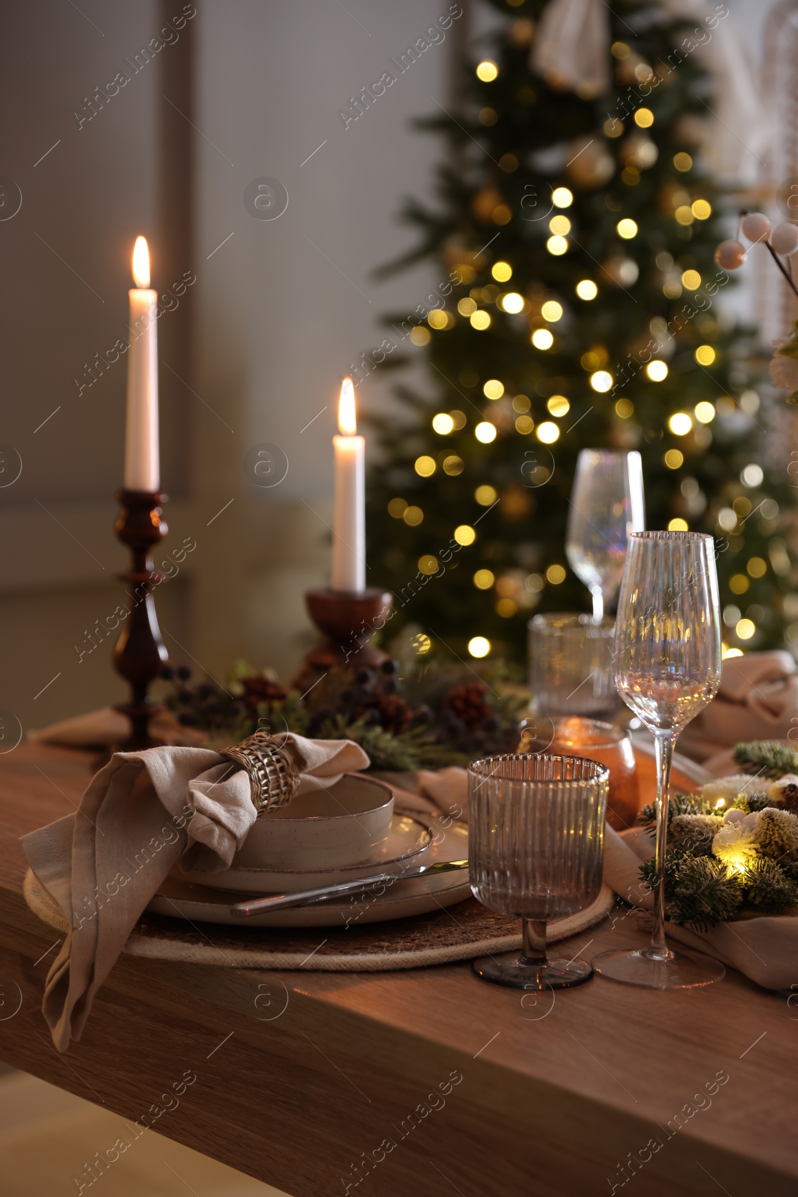 Photo of Christmas place setting with festive decor on wooden table in room