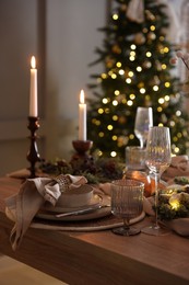 Photo of Christmas place setting with festive decor on wooden table in room