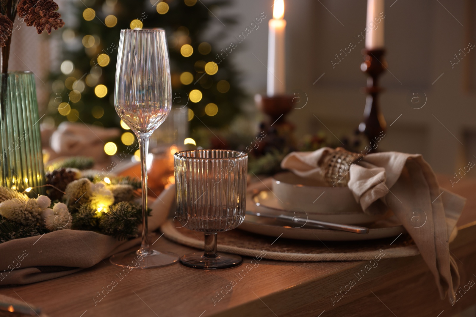 Photo of Christmas place setting with festive decor on wooden table in room, closeup