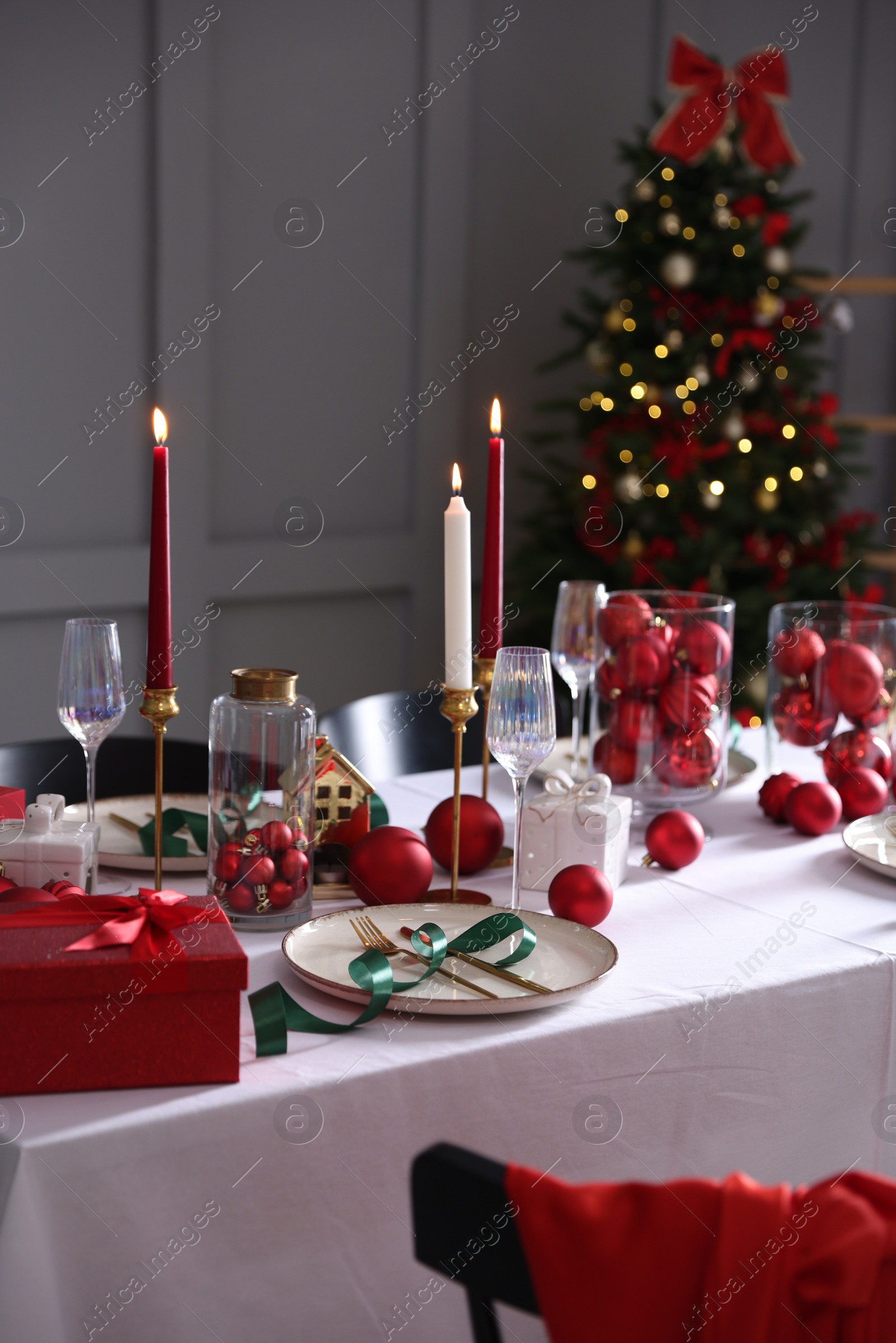 Photo of Christmas celebration. Festive table setting with dishware, glasses and decor