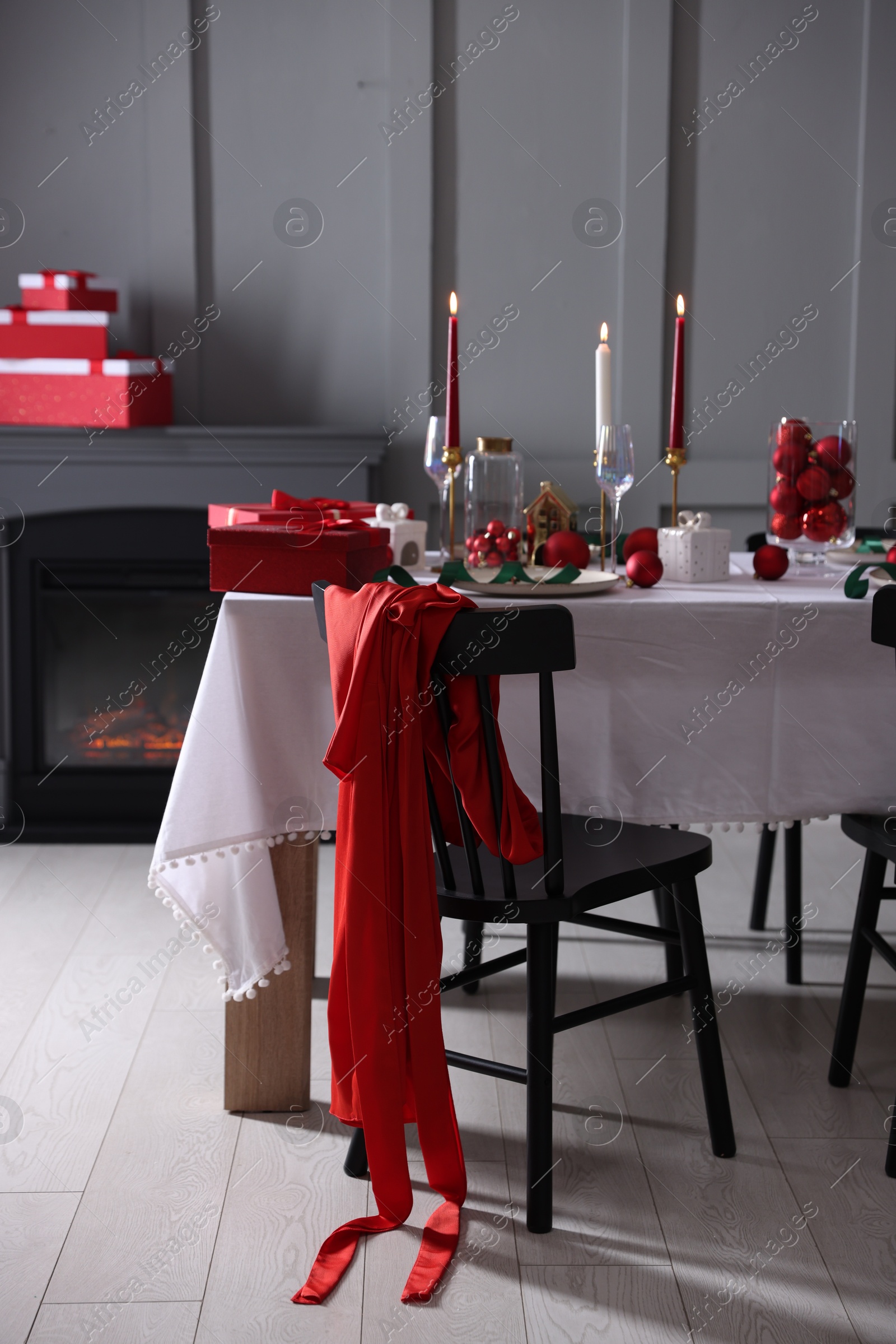 Photo of Christmas table setting with stylish dishware, glasses and burning candles in festive decorated room