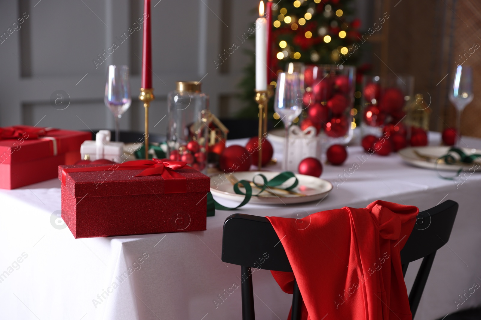 Photo of Christmas place setting with festive decor on table in room