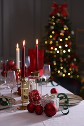 Photo of Christmas place setting with festive decor on table in room