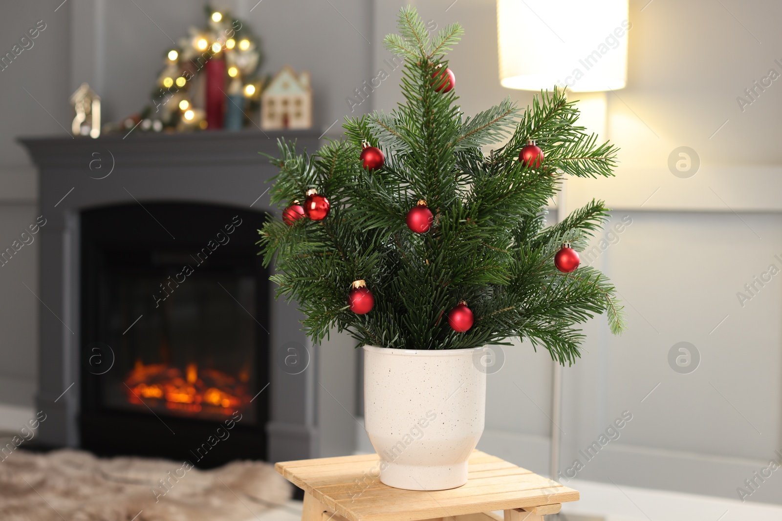 Photo of Beautiful Christmas composition of decorated fir tree branches on stool indoors