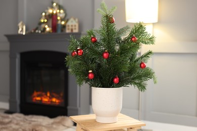 Photo of Beautiful Christmas composition of decorated fir tree branches on stool indoors