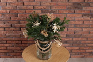 Photo of Beautiful Christmas composition of decorated fir tree branches on table near brick wall