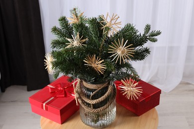 Photo of Beautiful composition of decorated fir tree branches and Christmas gifts on table indoors