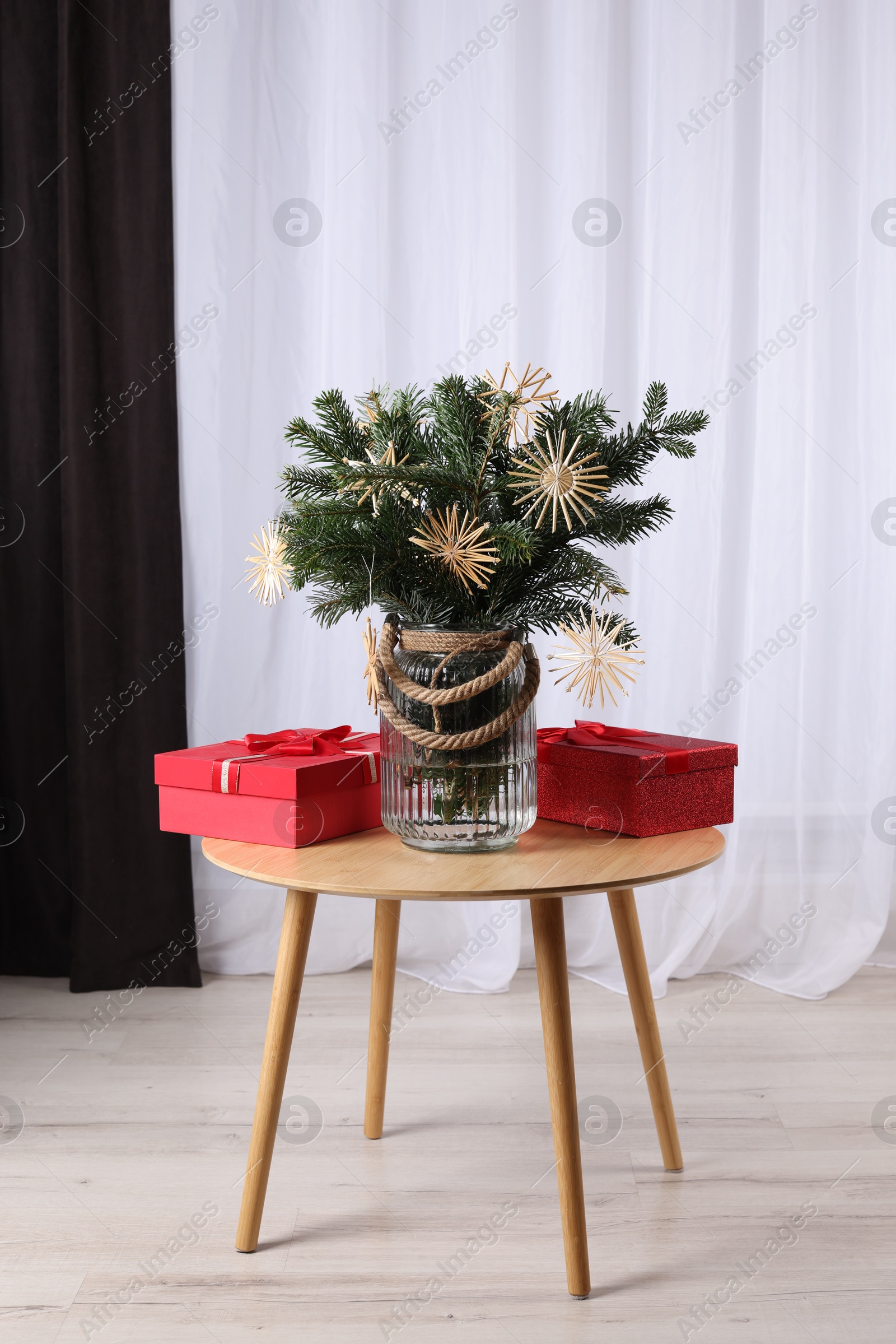 Photo of Beautiful composition of decorated fir tree branches and Christmas gifts on table indoors