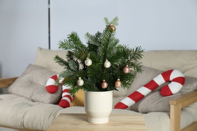 Photo of Decorated fir tree branches on table at home. Christmas decor