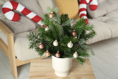 Photo of Decorated fir tree branches on table at home. Christmas decor