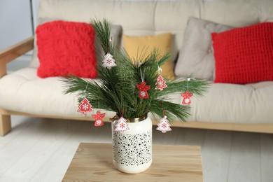 Photo of Decorated pine tree branches on table at home. Christmas decor