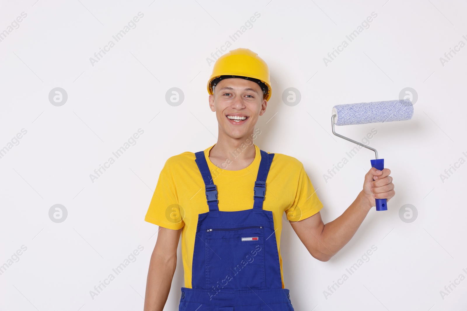 Photo of Portrait of young decorator with paint roller on white background