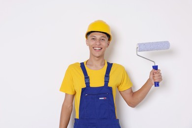 Photo of Portrait of young decorator with paint roller on white background