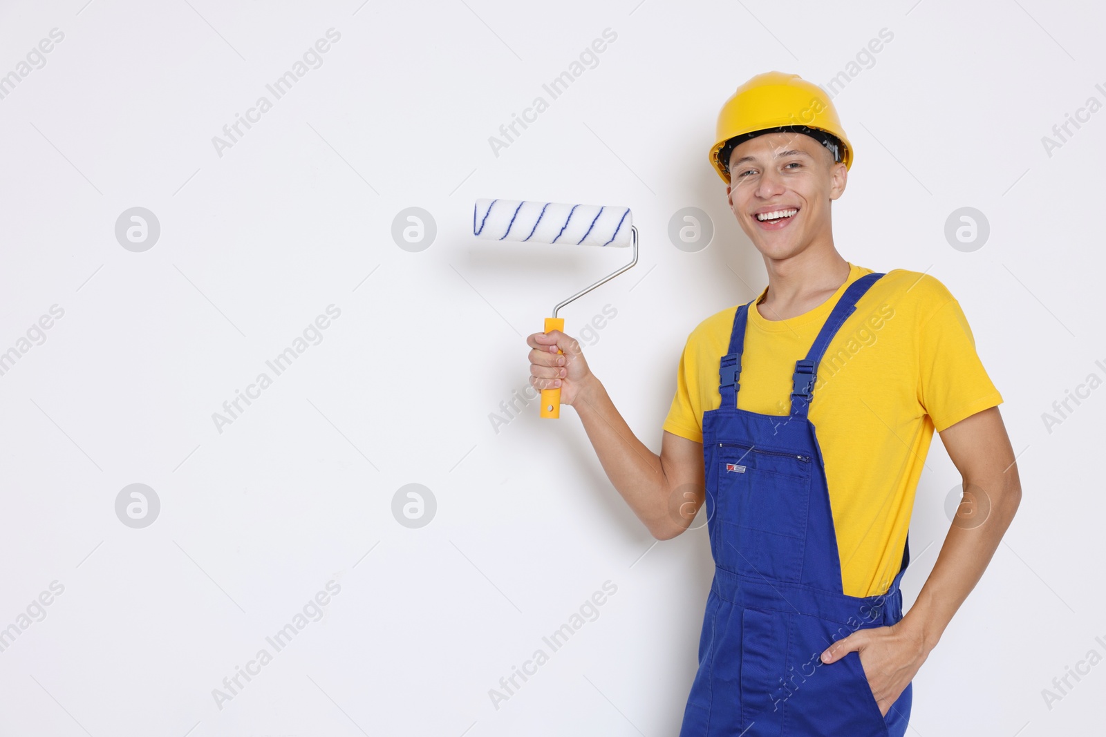 Photo of Portrait of young decorator with paint roller on white background, space for text