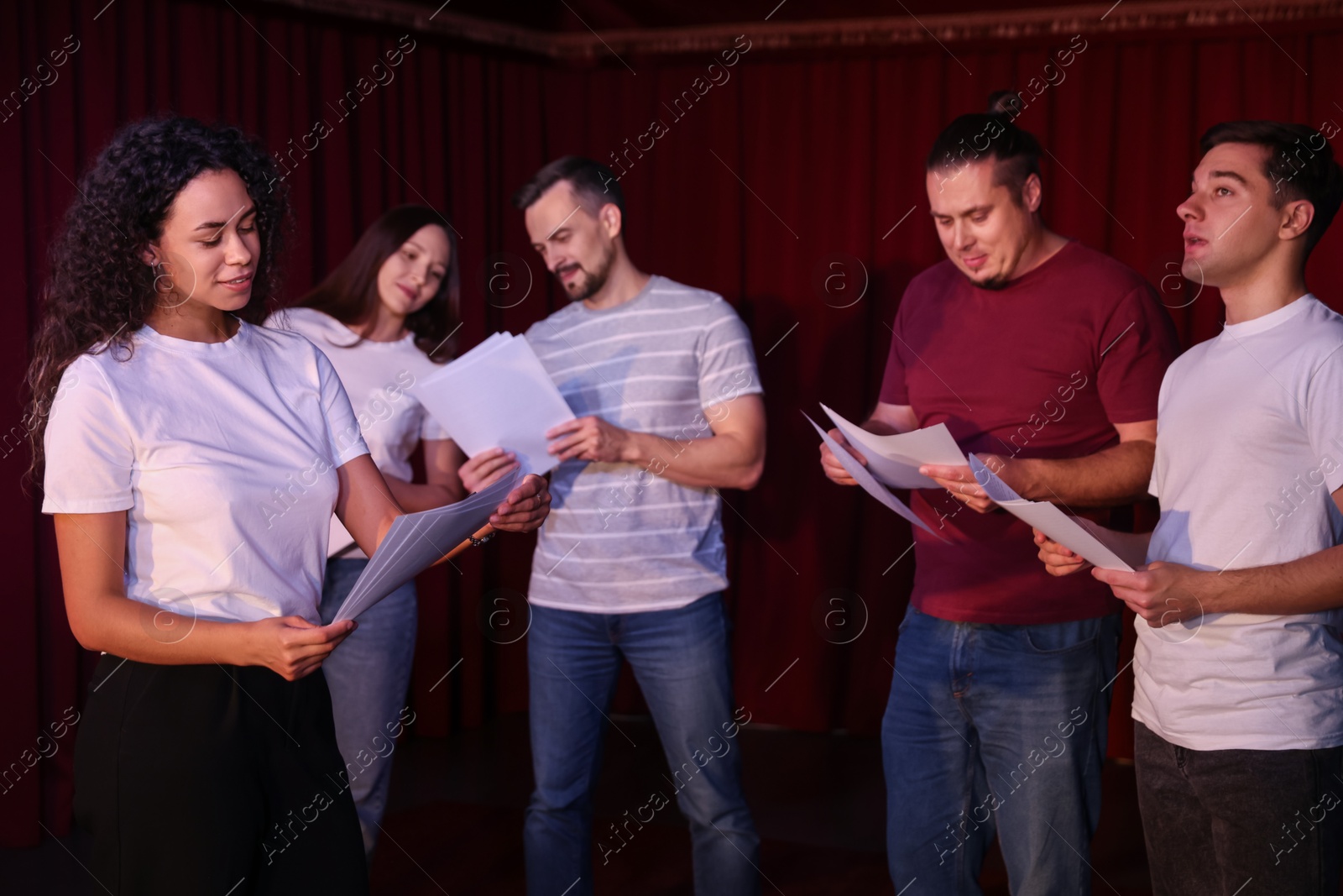 Photo of Professional actors with their scripts rehearsing in theatre