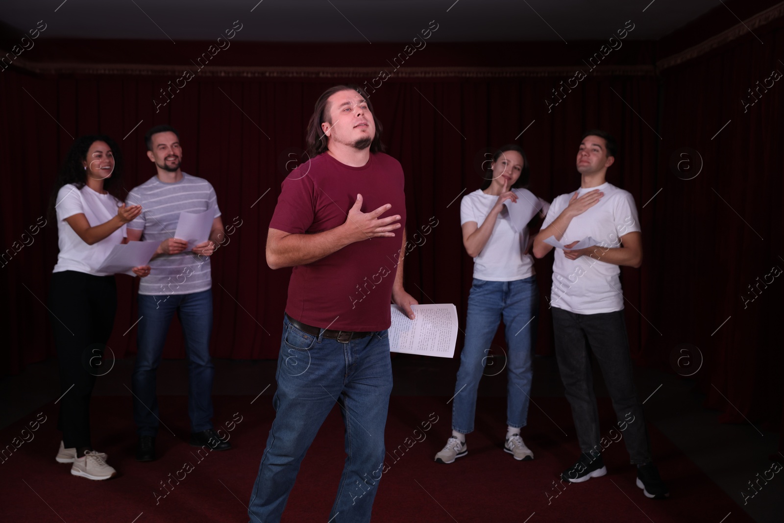 Photo of Professional actors with their scripts rehearsing in theatre