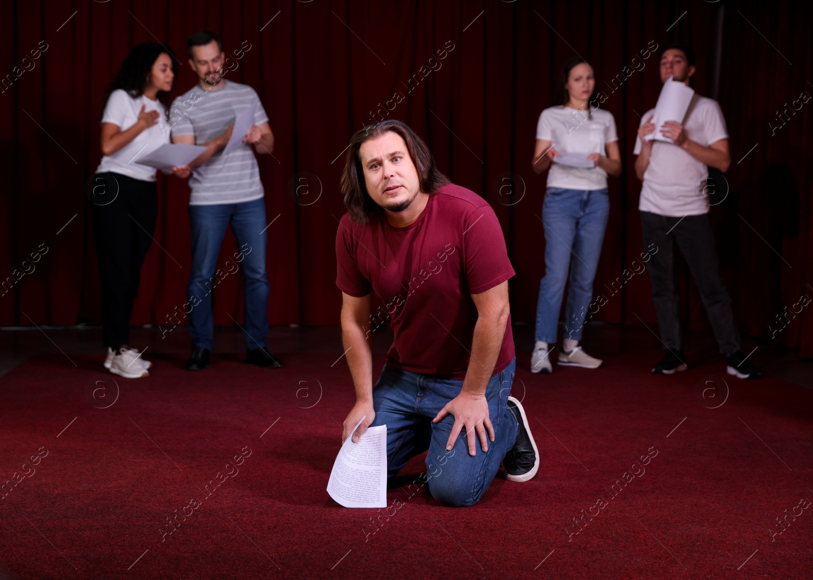 Photo of Professional actors with their scripts rehearsing in theatre