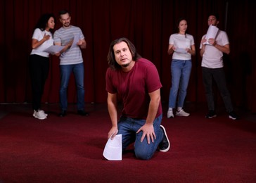 Photo of Professional actors with their scripts rehearsing in theatre