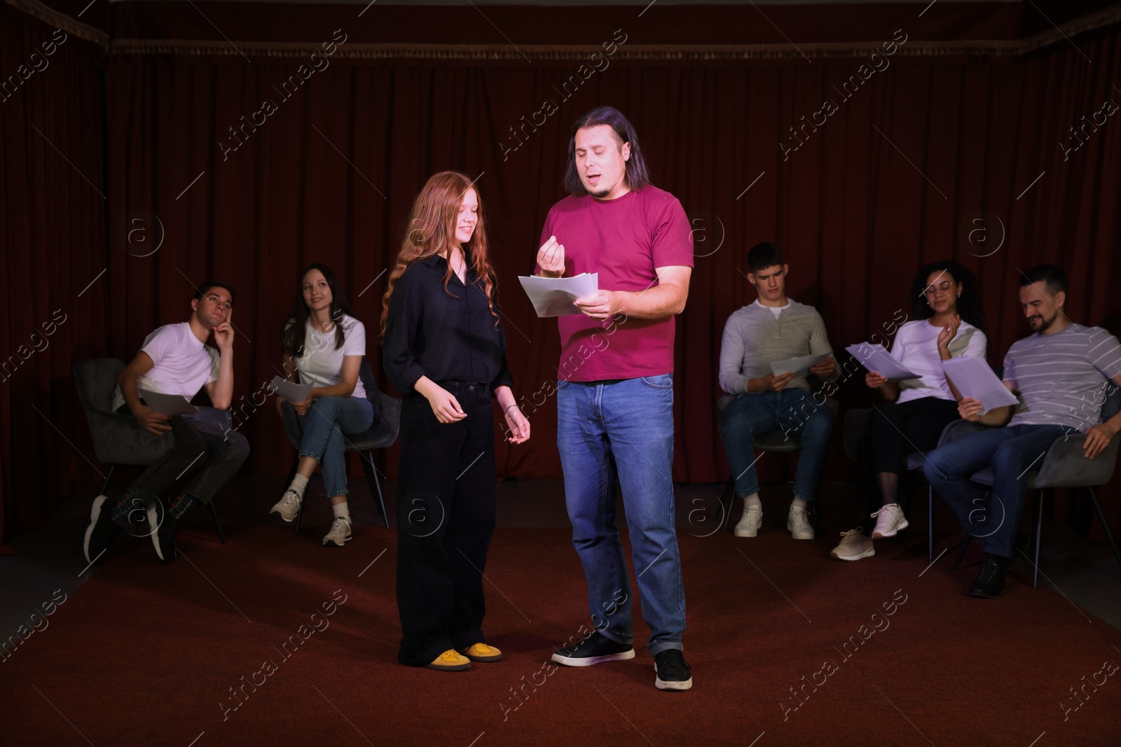 Photo of Professional actors with their scripts rehearsing in theatre