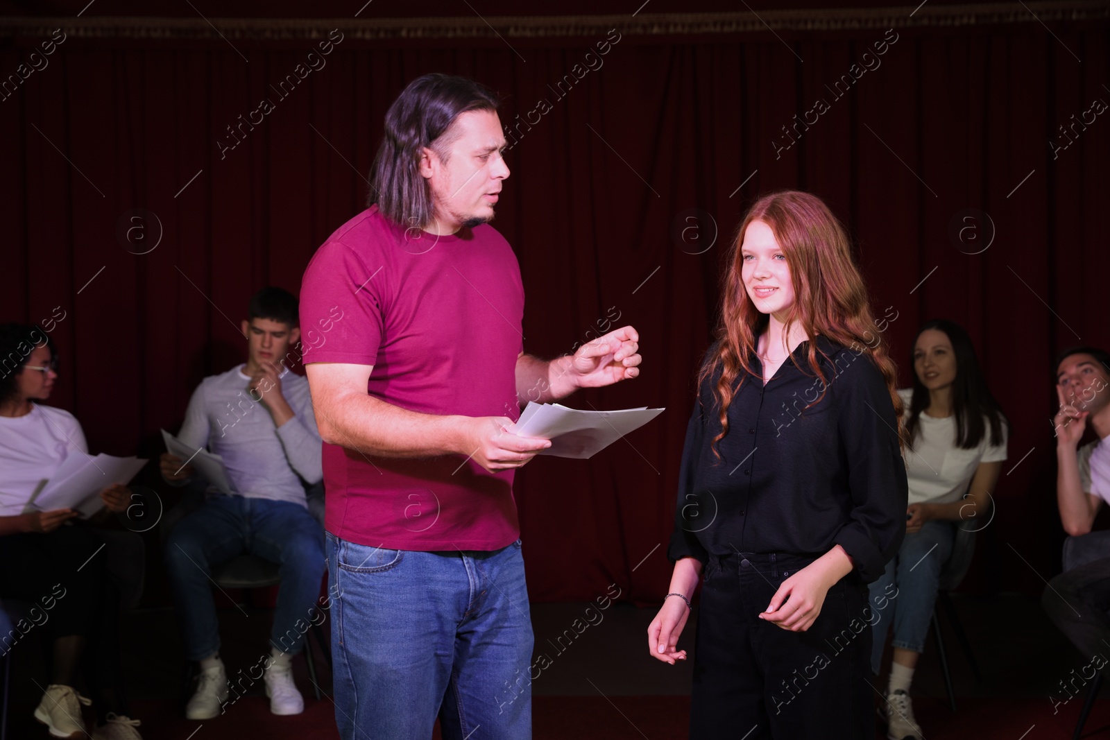 Photo of Professional actors with their scripts rehearsing in theatre