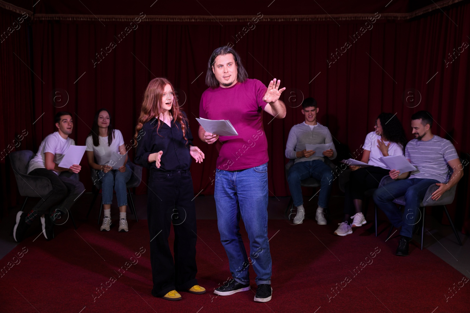 Photo of Professional actors with their scripts rehearsing in theatre