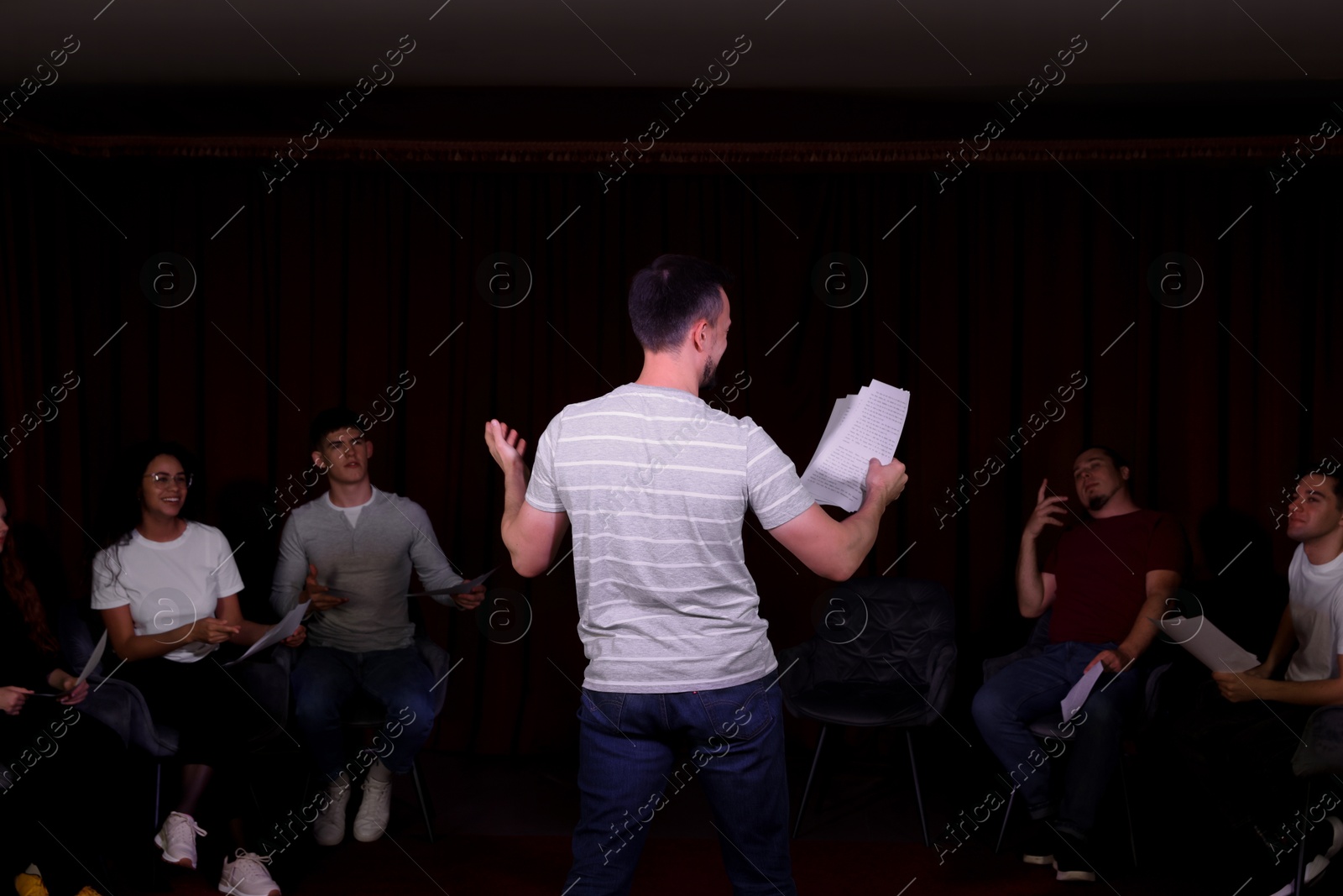 Photo of Professional actors with their scripts rehearsing in theatre