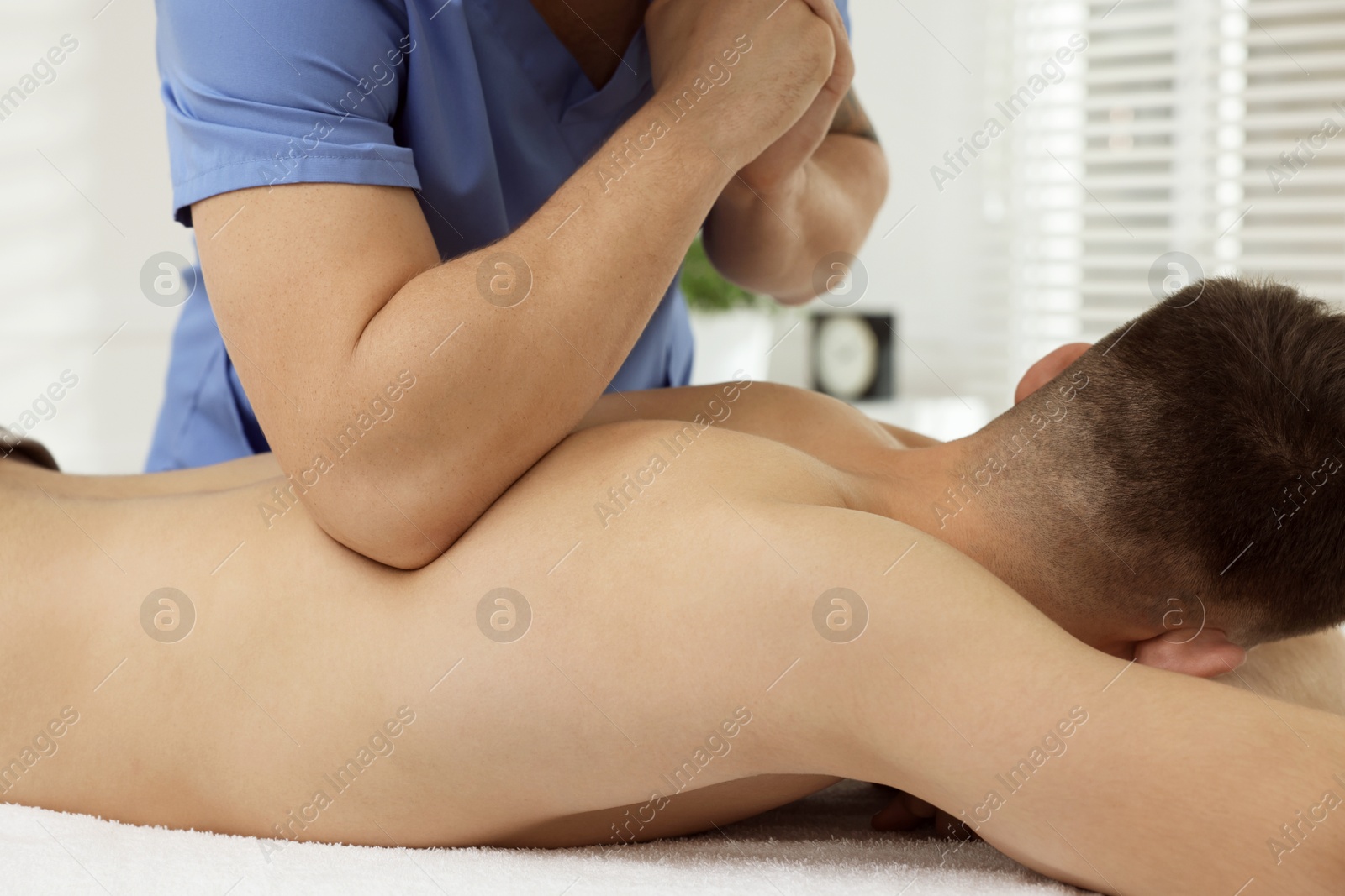 Photo of Osteopath massaging man's back in clinic, closeup. Manual therapy