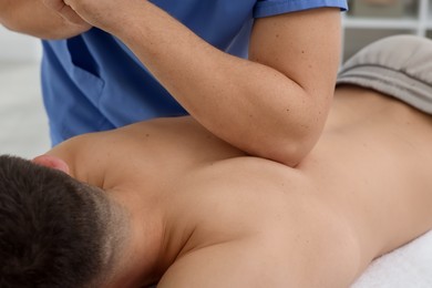 Photo of Osteopath massaging man's back in clinic, closeup. Manual therapy