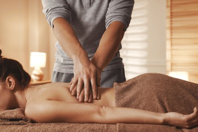 Photo of Osteopath massaging woman's back on couch indoors, closeup. Manual therapy