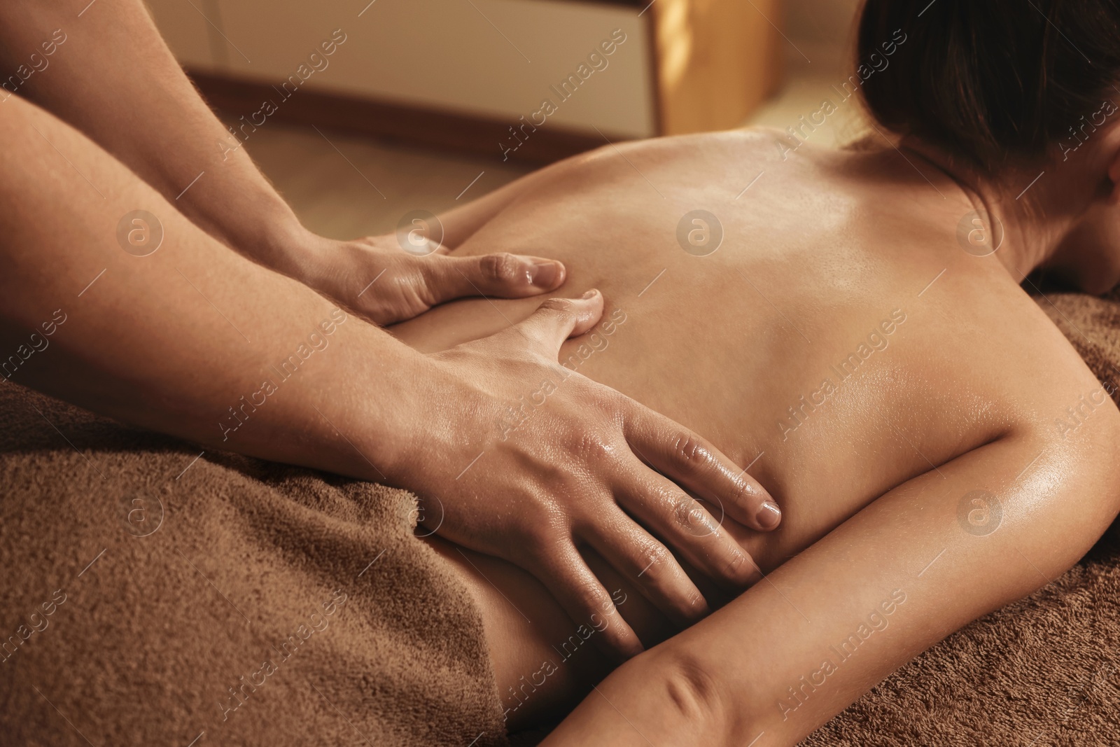 Photo of Osteopath massaging woman's back on couch indoors, closeup. Manual therapy