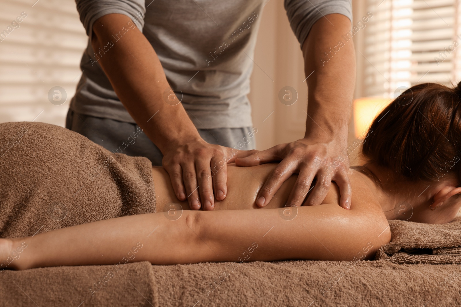 Photo of Osteopath massaging woman's back on couch indoors, closeup. Manual therapy