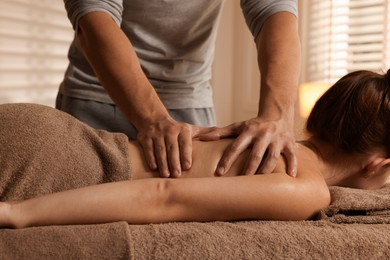 Photo of Osteopath massaging woman's back on couch indoors, closeup. Manual therapy