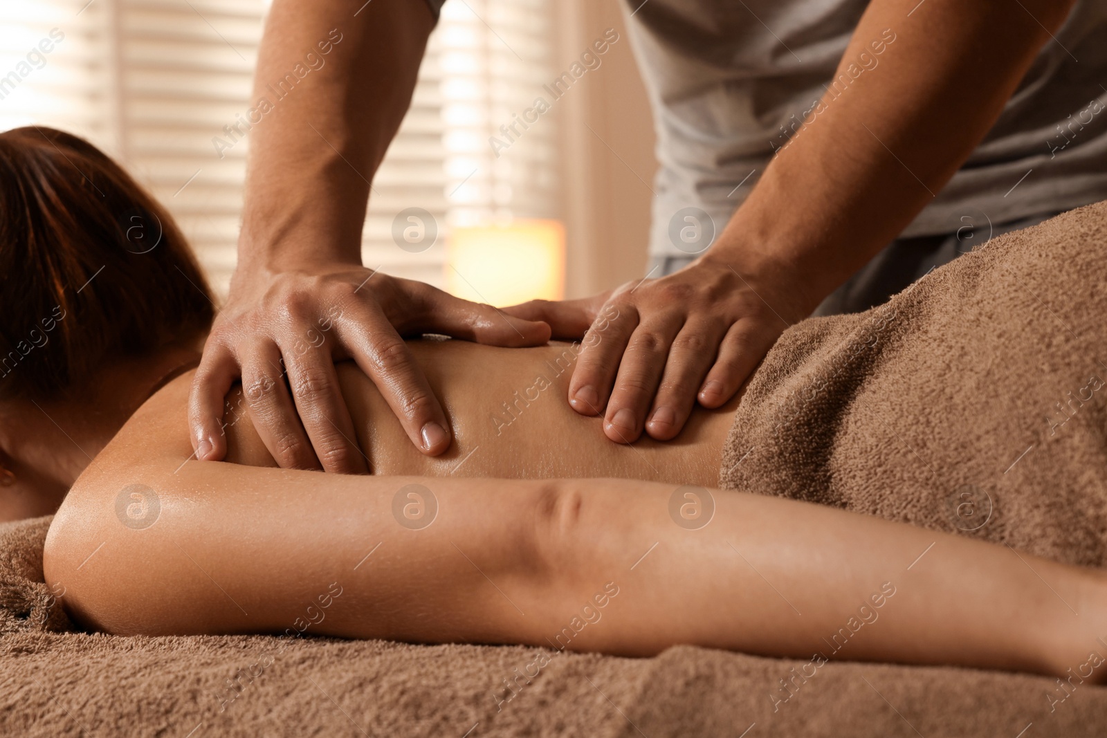 Photo of Osteopath massaging woman's back on couch indoors, closeup. Manual therapy