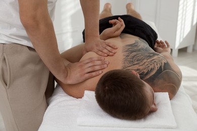 Massage therapist working with patient in clinic, closeup